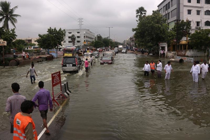 Vehicles and people navigate their way through a waterlogged street in Hyderabad.