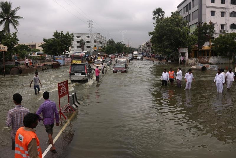 Click to enlarge Vehicles and people navigate their way through a waterlogged street in Hyderabad.
