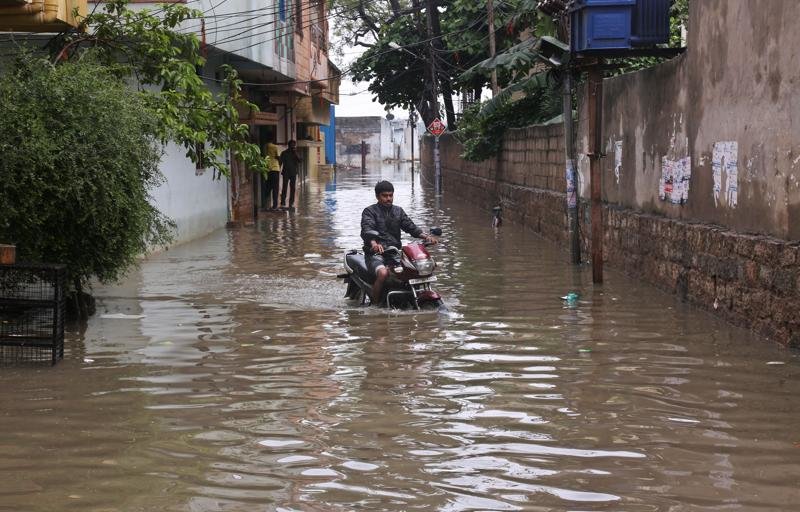 Man rides a motorbike through a waterlogged street in Hyderabad.