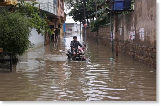 Man rides a motorbike through a waterlogged street in Hyderabad.
