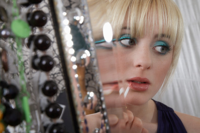 Teenage girl applying lip gloss. 
