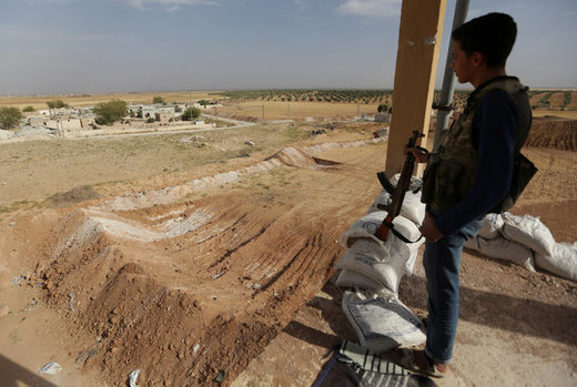 Click to enlarge A rebel fighter stands on a lookout point in Kafr-Brisha village