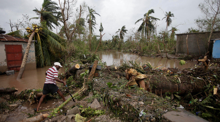 Click to enlarge A man cuts branches off fallen trees in a flooded area by a river after Hurricane Matthew in Les Cayes, Haiti, October 5, 2016.
