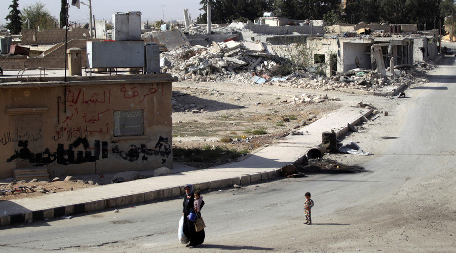 Click to enlarge A boy walks behind a woman carrying a child along a street in the northern Syrian town of al-Rai, in Aleppo