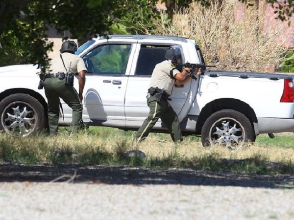 Peace officers point to a home on Cypress Road after gunshots where fired wounding at least one. Palm Springs, California