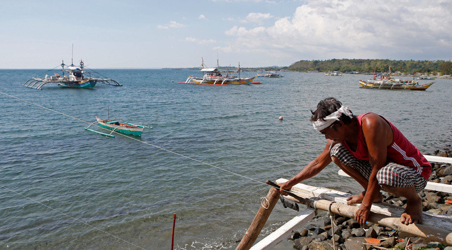 Click to enlarge A fisherman repairs his boat
