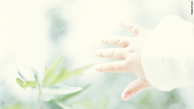 Click to enlarge child's hand reaching for flower
