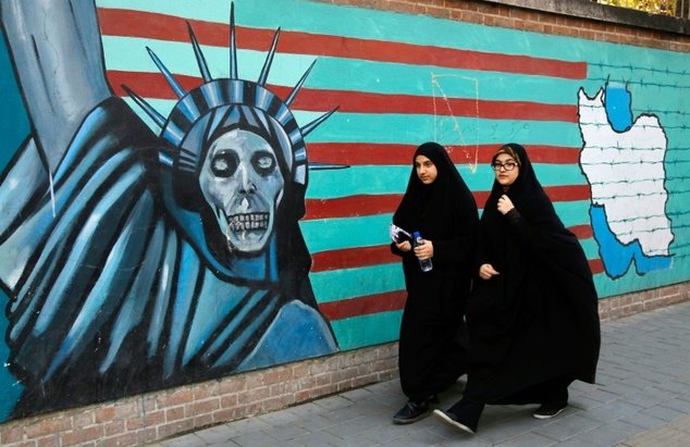 Iranian women walk past the former US embassy in Tehran