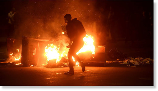 Click to enlarge A woman passes burning garbage during a demonstration in Oakland, California, U.S. following the election of Donald Trump as President of the United States November 9, 2016