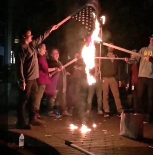 Hillary Clinton supporters burn a US flag in Portland, Oregon, during protests after Trump wins