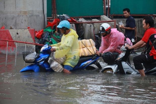 Motorcyclists slowly make their way along the flooded road at Pu Chao Saming Phrai intersection in Samut Prakan, Thailand on Tuesday morning