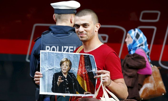 migrant holds a picture of German Chancellor Angela Merkel