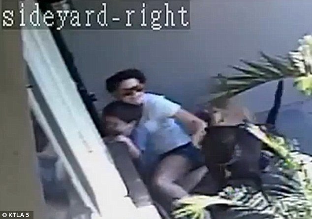 Click to enlarge Shocking attack: Surveillance footage from outside the Anaheim home show the mother attempting to fight off the two dogs at her front door, while protecting her son