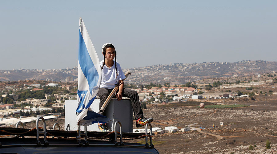 Click to enlarge boy sits near an israeli flag