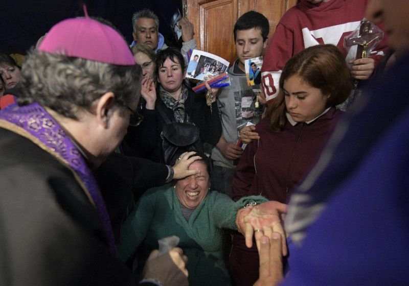 Bishop Manuel Acuna (L) performs a ritual at the 'El Buen Pastor' parish in Santos Lugares, on the outskirts of Buenos Aires