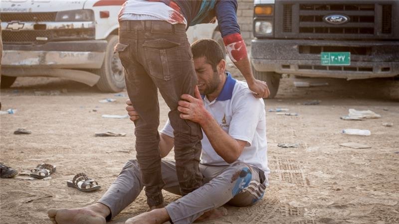 Click to enlarge Relatives of Mohammed, 15, comfort each other at an outdoor clinic in Mosul's Samah district after he was killed by a mortar attack minutes earlier