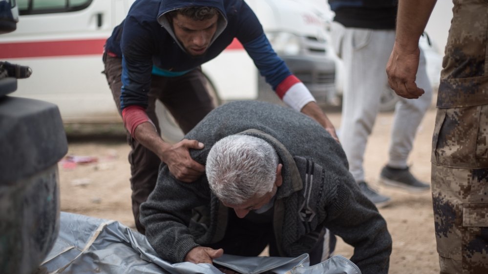 The father of Maytham, 15, opens the body bag containing his son at an outdoor clinic in Mosul's Samah district. Maytham was killed by a mortar attack minutes earlier