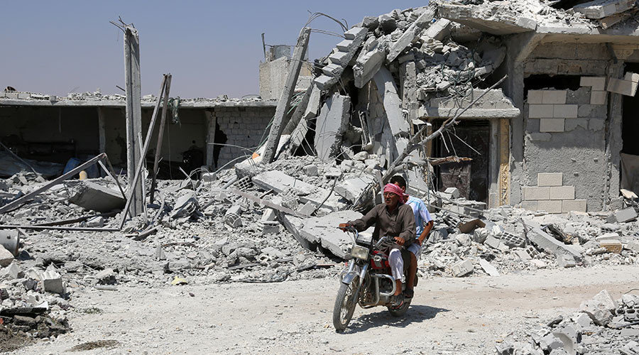 A Syrian man rides his motorcycle past collapsed buildings in the northern Syrian town of Manbij