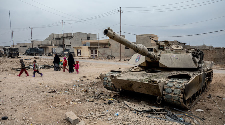 family walks past a destroyed M-1 Abrhams tank in Gogjali