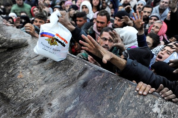 Click to enlarge Syrians who have been evacuated from eastern Aleppo, reach out for Russian food aid
