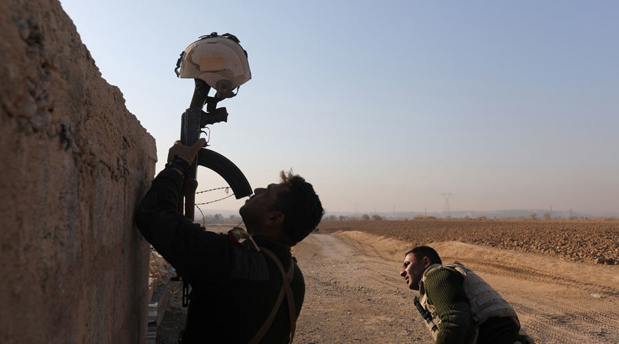 Iraqi soldier uses his rifle to hold up a helmet 