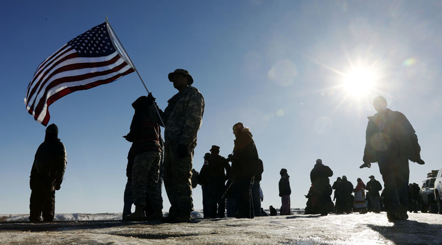 Veterans hold a US flag outside the Oceti Sakowin