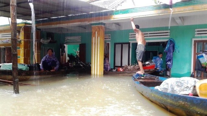 Residents of Quang Nam Province collect property from a flooded home.