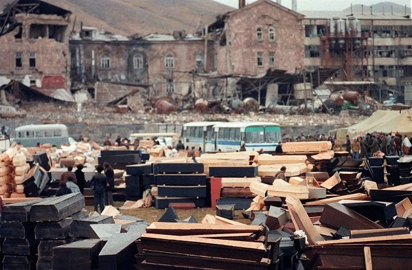 Coffins are piled up in the devastated town of Spitak