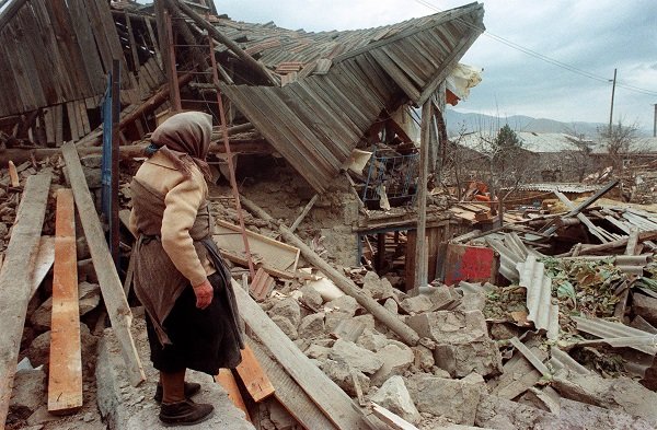 Click to enlarge woman looks at her destroyed house