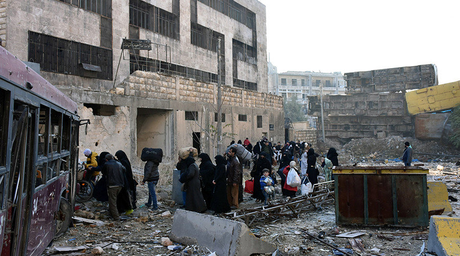 People, who evacuated the eastern districts of Aleppo, carry their belongings as they arrive in a government held area of Aleppo