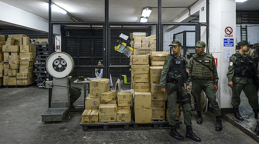 Members of the Venezuelan national guard stand next to boxes full of confiscated toys in a warehouse in Caracas on December 9, 2016