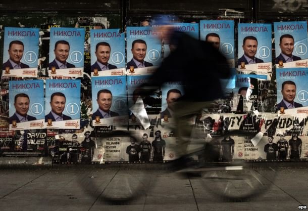 Click to enlarge man rides his bicycle past election posters