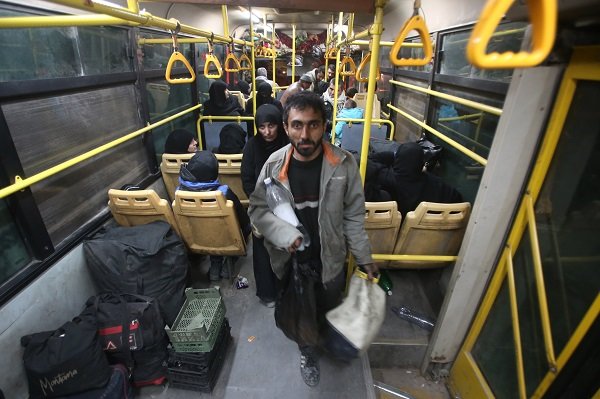 Syrian residents of the Old City of Aleppo stand in a bus