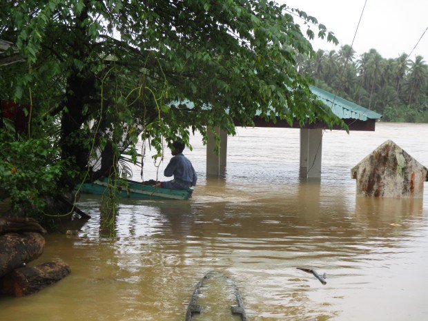 Click to enlarge A man uses his paddle boat to get around the flood waters in Taft, Eastern Samar.