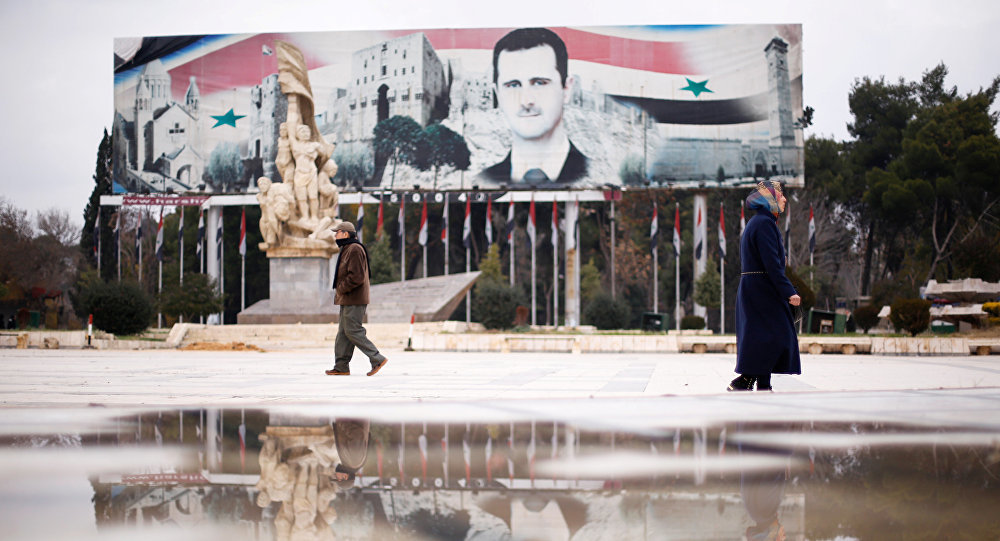 People walk past a billboard depicting Syria's President Bashar al-Assad at Saadallah al-Jabri Square, in the government controlled area of Aleppo, Syria December 17, 2016