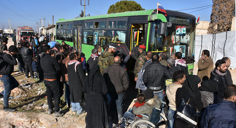 Syrian residents fleeing the violence, queue as they board a bus at a checkpoint, manned by pro-government forces, in the village of Aziza on the southwestern outskirts of the northern Syrian city of Aleppo on December 9, 2016