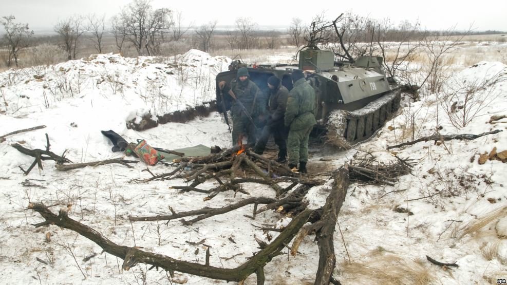 Donetsk rebels stand next to an armored military vehicle