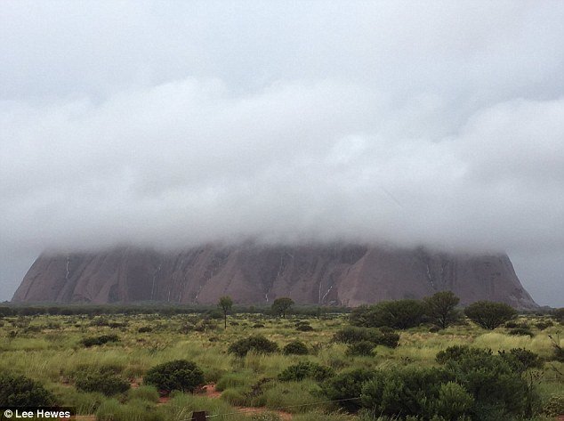 Flash flooding closed Uluru and forced a town to evacuate after a record 232 millimetres of rain fell in a single day with a thick low-lying white cloud obscured the top of the rock