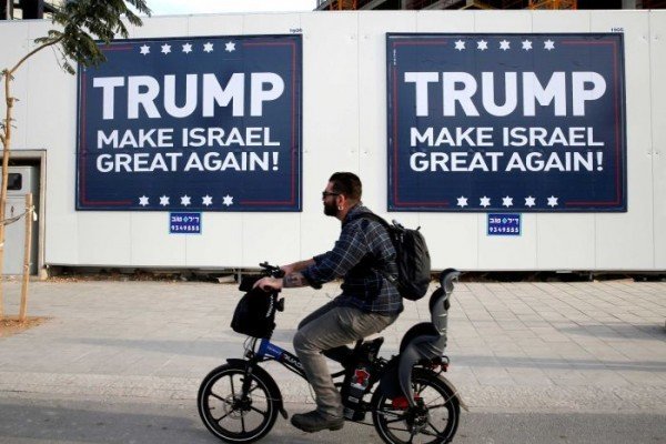 Click to enlarge Man rides past Trump posters