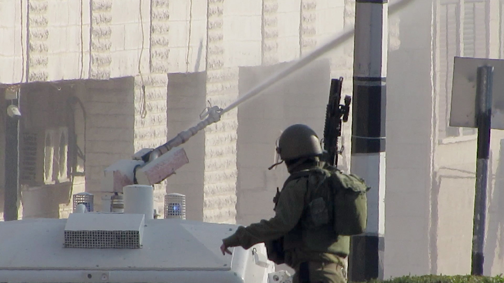 Click to enlarge An Israeli soldier clears out of the way as a specially-built IDF vehicle begins to douse Bethlehem in “skunk spray”, chemical warfare intended to make life miserable for the civilian population