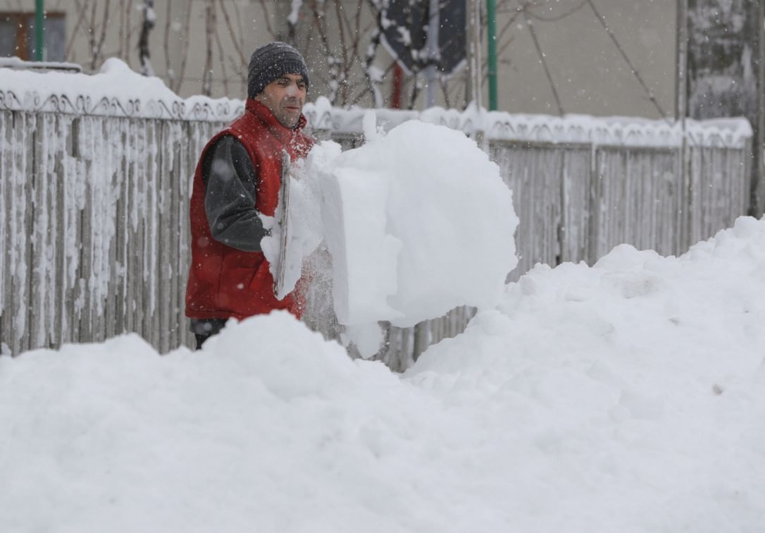 A man shovels snow outside his home in Pietrosani, Romania. The blizzard is expected to ease off late Friday.