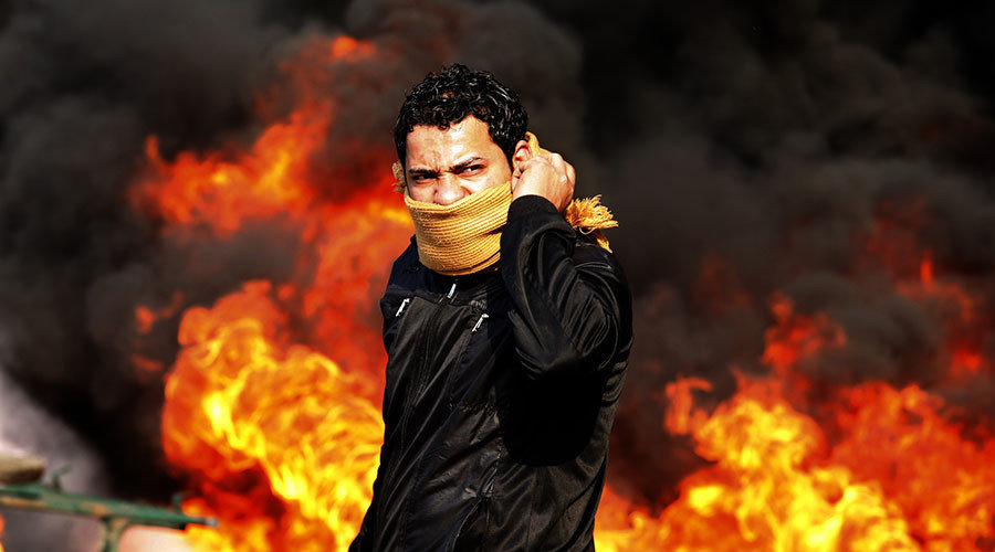 A protester stands in front of a burning barricade during a demonstration in Cairo 