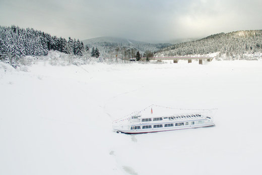 The excursion boat MS AquaMarin is locked in by snow and ice on the Okerstausee reservoir, Germany