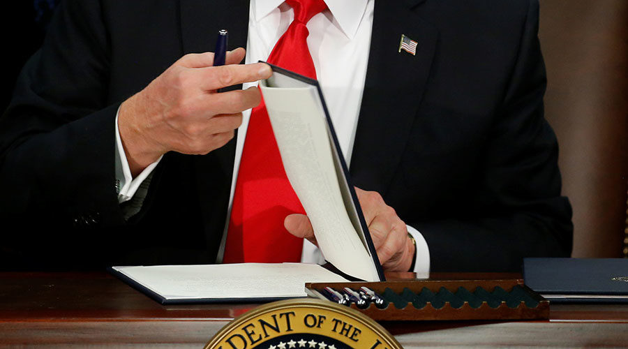 Click to enlarge Donald Trump prepares to sign