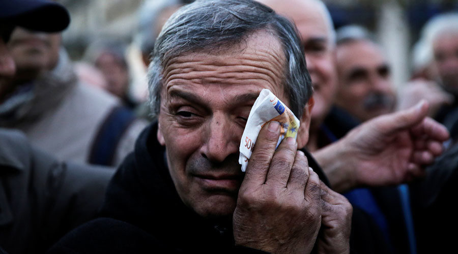 A Greek pensioner wipes his face with a fake euro banknote during a demonstration against government policies affecting pensioners in Athens