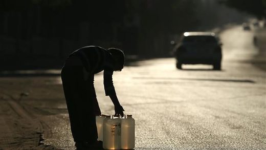 A Palestinian boy carries water in plastic canisters on a main road in Beit Lahia in the northern Gaza Strip