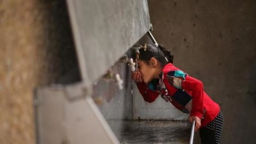 A Palestinian girl drinks water from a public tap in the Jabaliya refugee camp in the northern Gaza Strip
