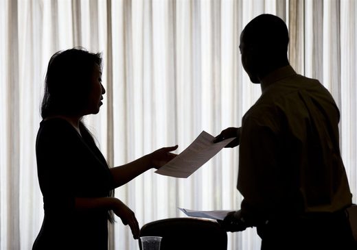 A recruiter, left, takes the resume of an applicant during a job fair, in Philadelphia