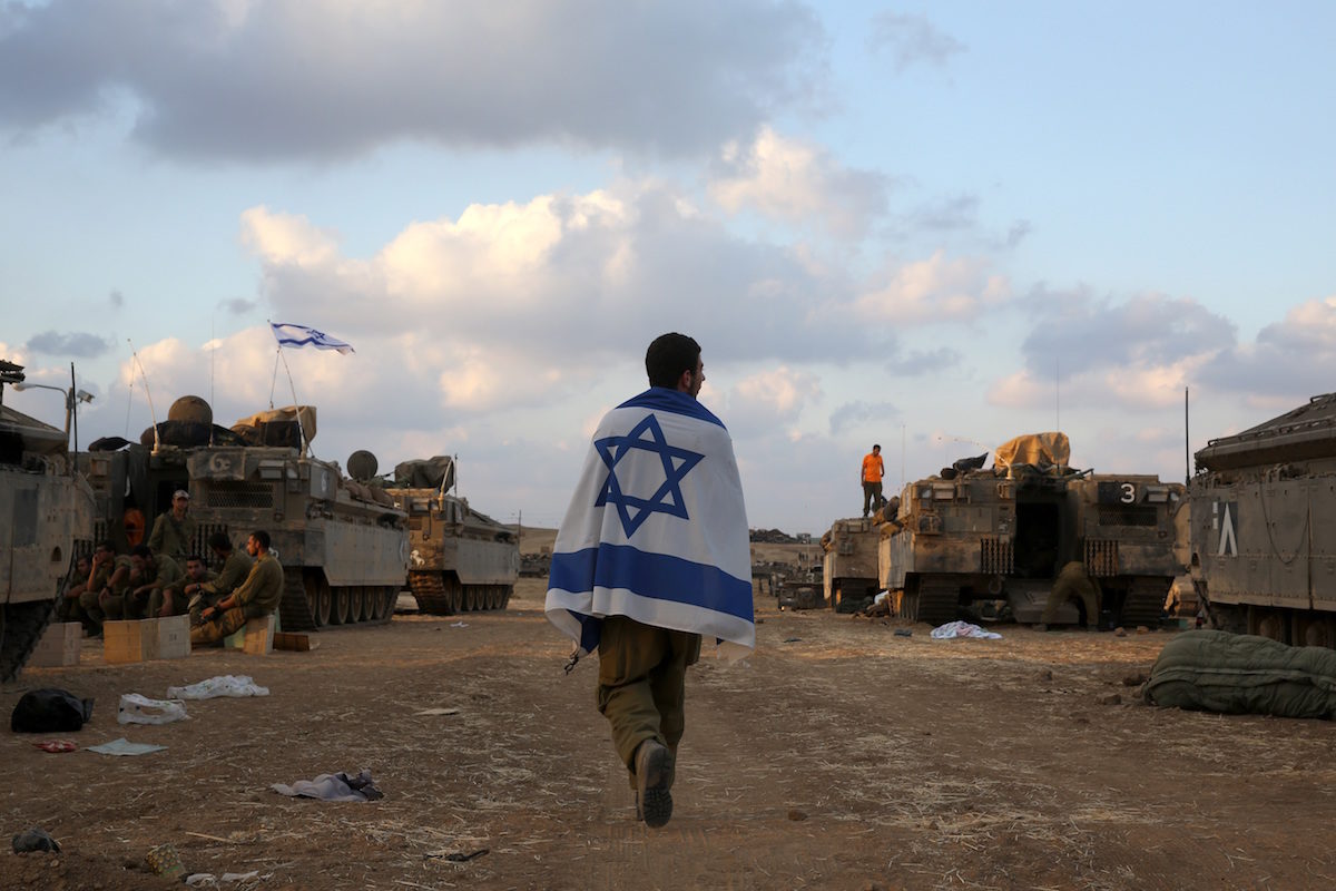 Israeli soldier walks wrapped in an Israeli flag
