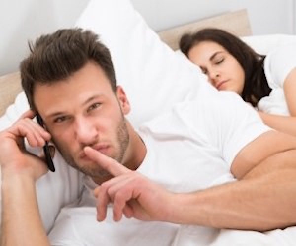 whispering man in bed on phone